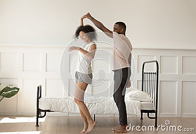 Happy barefoot african american loving family couple dancing in bedroom. Stock Photo