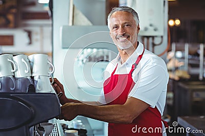 Happy barista smiling at camera and using the coffee machine Stock Photo