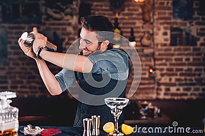 happy barman using shaker for cocktail preparation. Portrait of barman making tequila based margarita at local pub Stock Photo