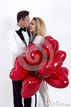 Happy beautiful couple posing on white background and holding balloons heart. Valentine`s day. Stock Photo