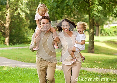 Happy beautiful family of four running in park Stock Photo