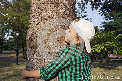 Happy beautiful girl hugging big tree in park . Loving nature . Stock Photo