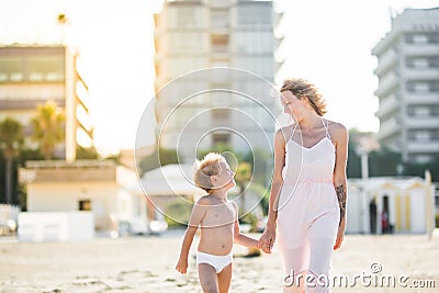 Happy beautiful mom goes hand in hand with cute child at the beach Stock Photo