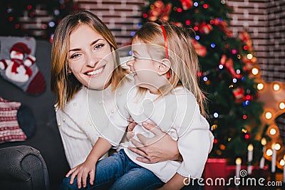 Happy beautiful mother and her little daughter posing near Christmas tree in a holiday interior Stock Photo