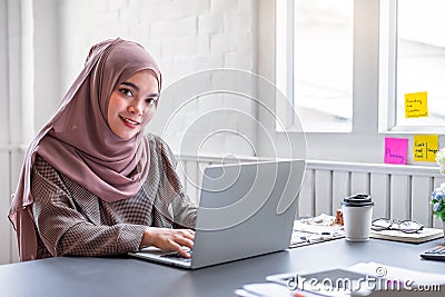 Happy beautiful muslim business woman brown hijab working about financial with business report and calculator in home office Stock Photo