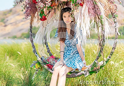 Happy beautiful woman having relax time on a flower swing in nature field for nature hapiness lifestyle Stock Photo