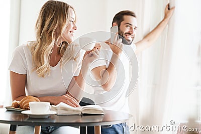 Happy beautiful young couple having breakfast at the kitchen table Stock Photo