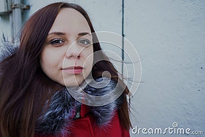 Happy beautiful young girl in a red jacket posing outside on a cloudy day Stock Photo