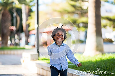 Happy and beautiful young kid black race african with ethnic alternative hair playing and runnig in a playground with and have Stock Photo