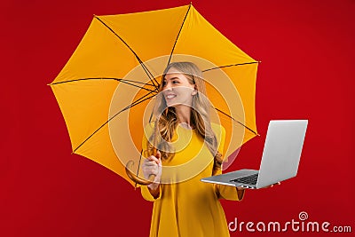Happy beautiful young woman with a parasol using the laptop on a red background Stock Photo
