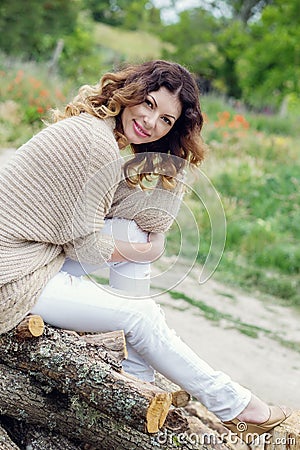 Happy beautiful young woman sitting on logs Stock Photo