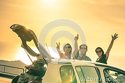 Happy best friends cheering by car road trip at sunset Stock Photo