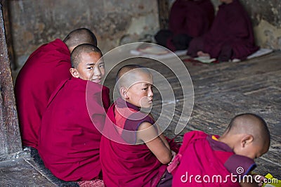 A happy Bhutanese young novice monk turn his head to smile when during study , Bhutan Editorial Stock Photo
