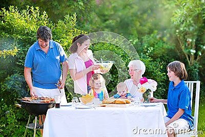 Happy big family eating grilled meat in garden Stock Photo