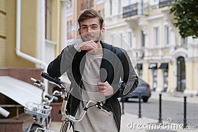 Happy bike messenger with backpack stands near bicycle and look at the camera Stock Photo