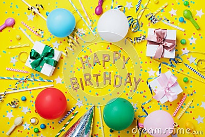 Happy birthday background or greeting flyer. Colorful holiday supplies on yellow table top view. Flat lay style. Stock Photo