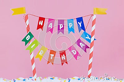 Happy Birthday banner on candy striped poles standing in white icing covered with sprinkles Stock Photo