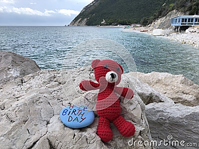 Happy Birthday message on a stone with a red wool bear Stock Photo