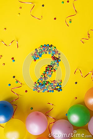 Happy Birthday number 2 made of candies with colorful balloons on yellow background Stock Photo