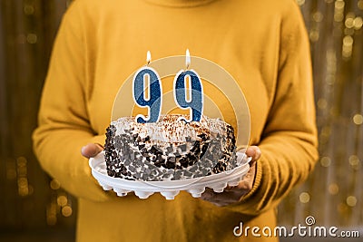 Happy birthday. Woman holding fresh delicious birthday cake with burning candle number 99, close up. Celebration of Stock Photo
