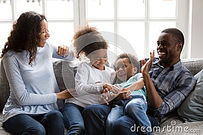 Happy black family laughing playing tickling children at home Stock Photo