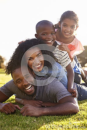 Happy black family lying in a pile on grass outdoors Stock Photo