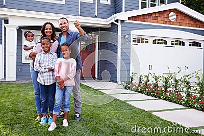 Happy black family standing outside their house, dad holding the key Stock Photo