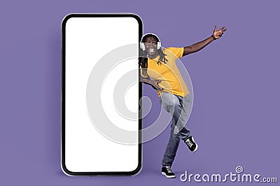 Happy black guy listening to muisc, using wireless headset Stock Photo