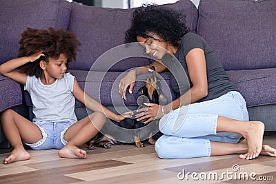 Happy black mom and daughter relax having fun with dog Stock Photo