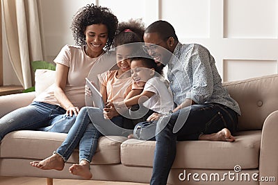 Happy black parents and children using digital tablet on sofa Stock Photo