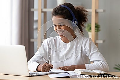 Happy black pupil in headphones doing school homework Stock Photo