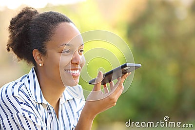 Happy black woman dictating message on cell phone Stock Photo