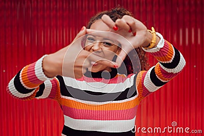 Happy, black woman and finger frame over eyes for funny face expression on red background. Fashion, comic and positive Stock Photo