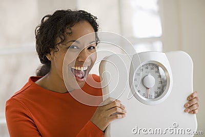 Happy black woman holding scale Stock Photo