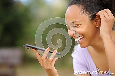 Happy black woman laughing dictating message on phone Stock Photo