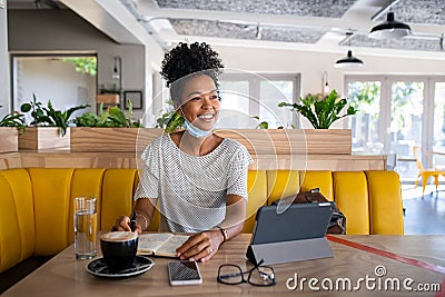 Happy black woman with lowered mask looking away Stock Photo