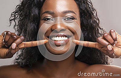 Happy black woman pointing at her perfect white teeth Stock Photo