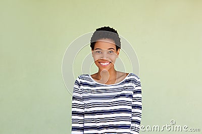 Happy black woman in striped shirt smiling by green background Stock Photo