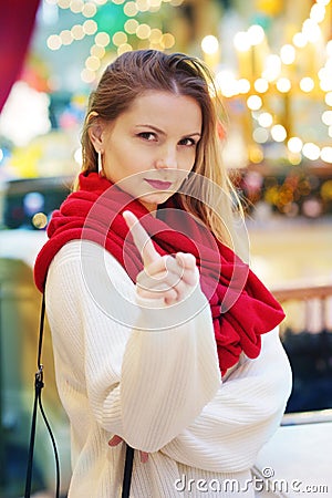 happy blond girl in red scarf show warning sign with point finger Stock Photo