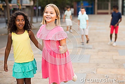 Happy blonde preteen girl walking with african american girl playmate Stock Photo