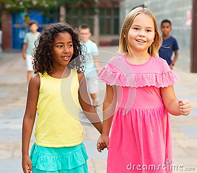Happy blonde preteen girl walking with african american girl playmate Stock Photo