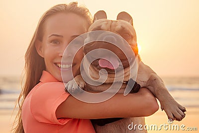 Happy blonde woman with french bulldog on india goa beach at sunset Stock Photo