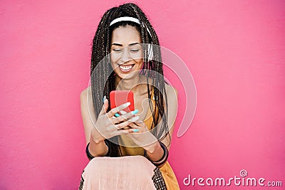 Happy bohemian influencer woman listening playlist music with pink background - Focus on face Stock Photo