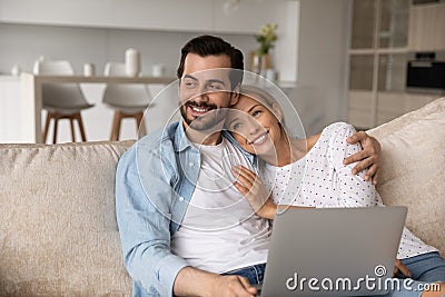 Happy bonding dreamy young family couple using computer. Stock Photo