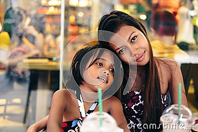 Happy bonding of two sisters in a cafe drinking ice cold shake Stock Photo