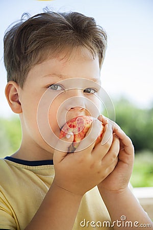 Happy boy biting the apple, A child with a fruit. Kid eating fresh pear Stock Photo