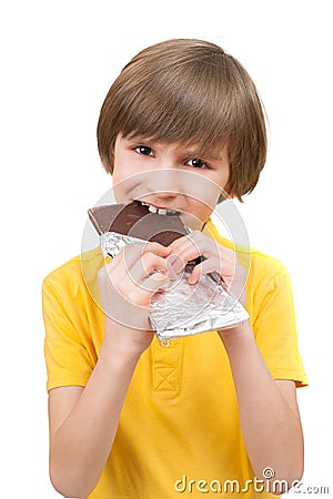 A happy boy is biting a stick of chocolate Stock Photo