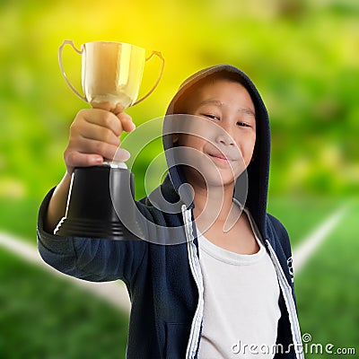 Happy boy in blue hood jacket holding trophy Stock Photo