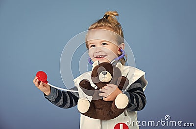 Happy boy in doctor uniform examine toy pet with stethoscope Stock Photo