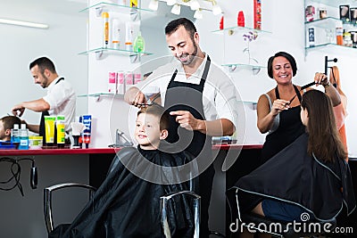 Happy boy in elementary school age getting hairdo of man Stock Photo